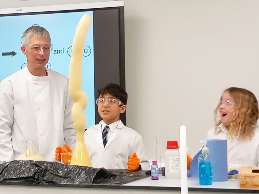 a teacher looking at 2 students finish a science experiment