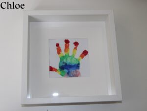 A rainbow painted hand print in a frame