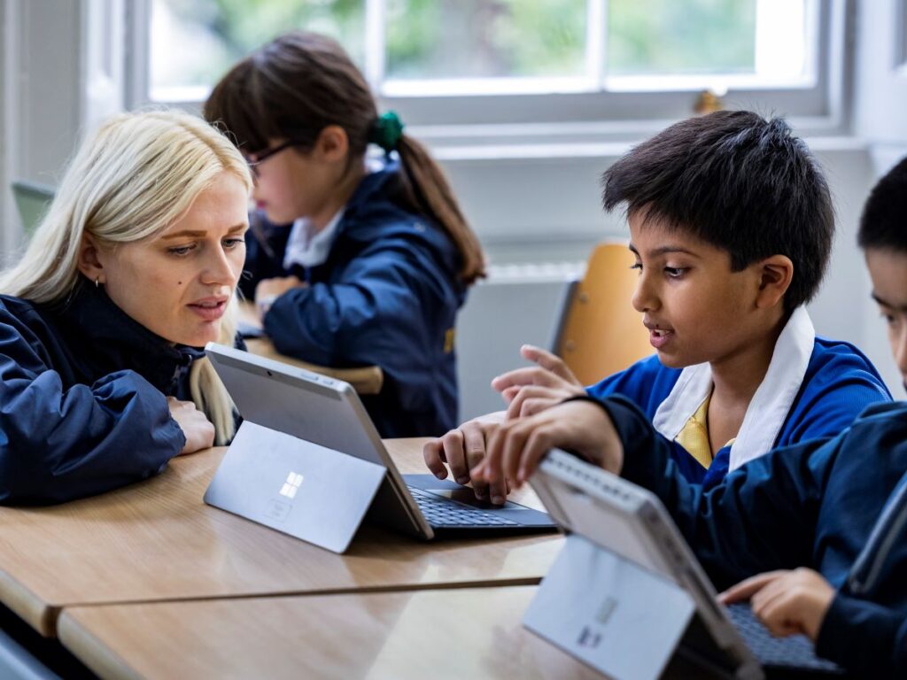 Student working on a tablet with his teacher