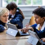 Student working on a tablet with his teacher