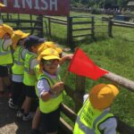 children in hi-vis jackets leaning against a fence